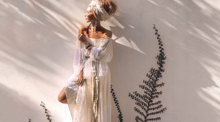 Woman wearing a white boho maxi dress with bohemian jewelry layered.