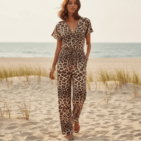 Woman wearing a boho leopard print wide leg jumpsuit with short flutter sleeves, V-neckline, adjustable drawstring waist, and side pockets.