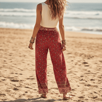 Back of woman wearing Crimson Meadow boho wide leg pants with functional side pockets, a high waist drawstring waistband, lightweight rayon fabric, and a flowy red floral palazzo silhouette featuring a floral and butterfly-inspired print.