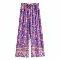 Wild Orchid boho wide leg pants with functional side pockets, a high waist drawstring waistband, lightweight rayon fabric, and a flowy purple floral palazzo silhouette with a vibrant botanical print.
