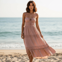 Woman wearing a dusty rose boho backless tie-back maxi dress with an open back, flowing A-line silhouette, elastic waist, and ankle-length hem on the beach.
