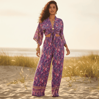 Woman wearing a boho purple floral kimono and wide leg pants set with a tie-front top, relaxed fit, and lightweight bohemian vacation style.