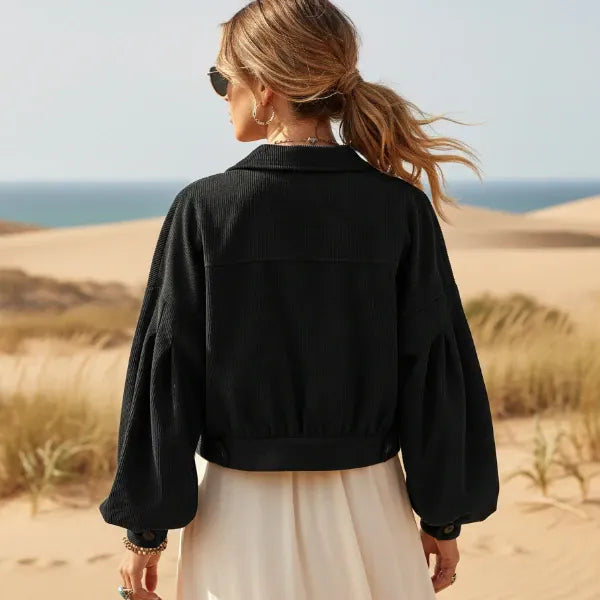 Back of a woman wearing a black boho cropped corduroy jacket with lantern sleeves and button front