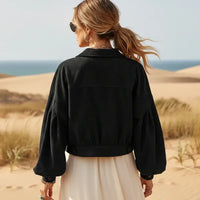 Back of a woman wearing a black boho cropped corduroy jacket with lantern sleeves and button front