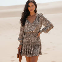 Woman wearing leopard print long sleeve boho mini dress with V-neck and ruffle hem