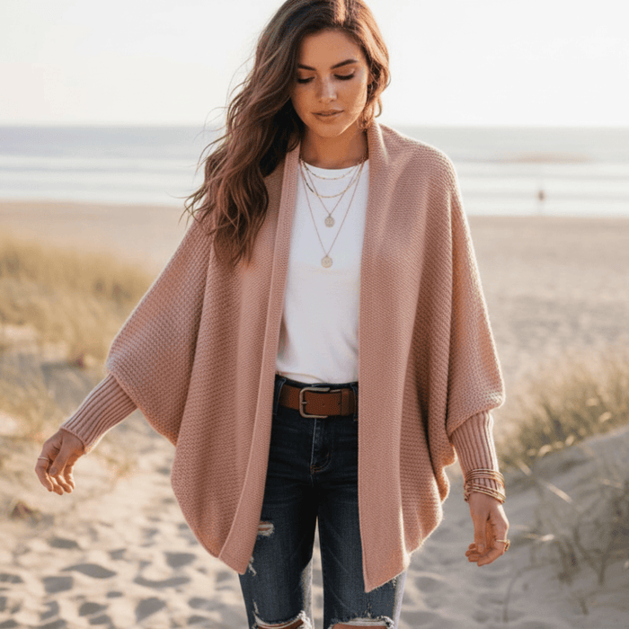Woman wearing a dusty rose pink oversized batwing knit cardigan with open front, long sleeves, ribbed cuffs, and a relaxed draped fit