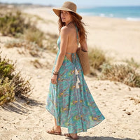 Back of colorful green boho floral maxi dress with an open-back halter design, adjustable ties, and an asymmetrical flowing skirt.