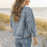 Back of a woman wearing light blue denim jacket with leopard print patchwork, front pockets and button closure