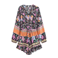 Black floral boho romper with long balloon sleeves, V-neck button front, tassel drawstring waist, colorful floral print, and ruffled shorts.