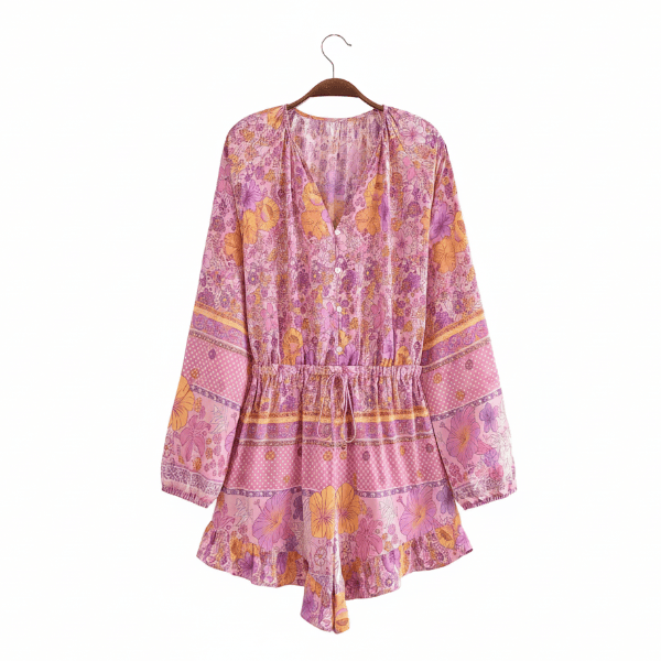 Pink floral boho romper with long balloon sleeves, decorative button-front V-neckline, tassel drawstring waist, and ruffled shorts.