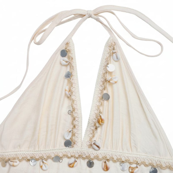 Close up of white boho halter open back maxi dress with tiered flowy skirt and shell details