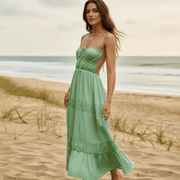 Woman wearing a light green boho backless tie-back maxi dress with an open back, flowing A-line silhouette, elastic waist, and ankle-length hem on the beach.
