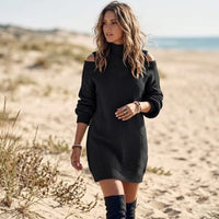 Woman wearing a black cable knit mini sweater dress with cold shoulder cutouts, mock neckline, and long lantern sleeves.