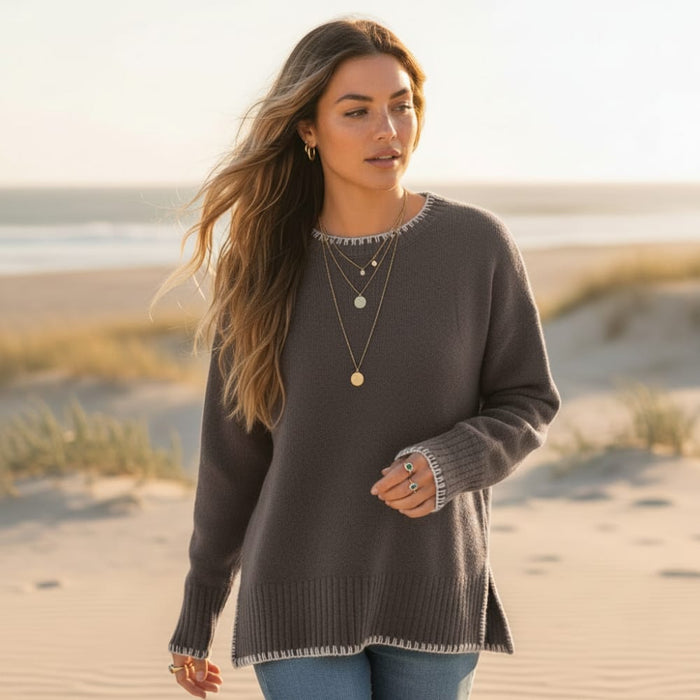 Woman wearing a taupe brown boho loose fit knit pullover sweater with long sleeves, contrast stitching and side slit hem