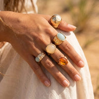 Five-piece vintage boho chunky gold ring set featuring hammered metal textures and blue, ivory, and amber stone-look accents.