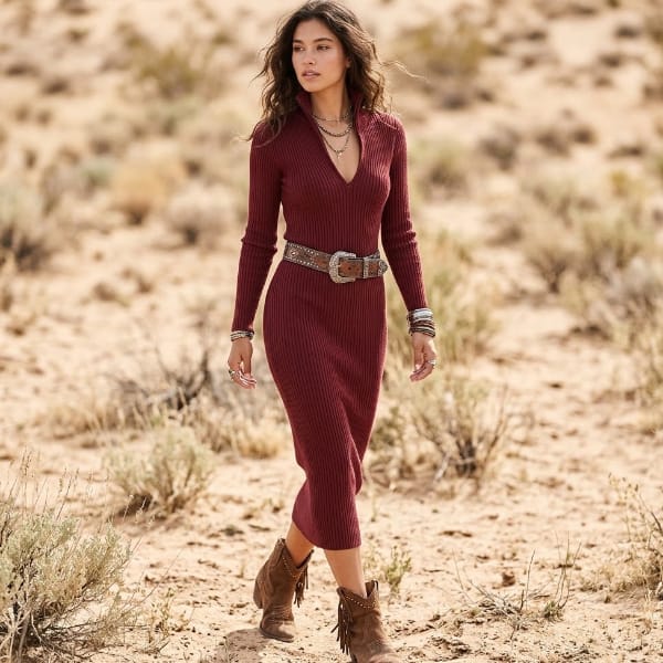 Woman wearing a burgundy ribbed knit midi sweater dress with long sleeves, deep V-neckline, fitted bodycon silhouette, and brown belt.