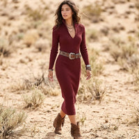 Woman wearing a burgundy ribbed knit midi sweater dress with long sleeves, deep V-neckline, fitted bodycon silhouette, and brown belt.