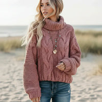 Woman wearing dusty mauve boho chunky knit turtleneck sweater with wide sleeves