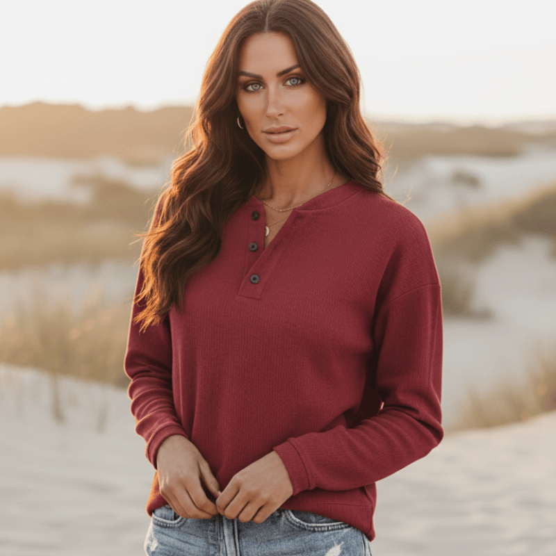 Woman wearing a burgundy casual long sleeve Henley top with partial button neckline and relaxed fit