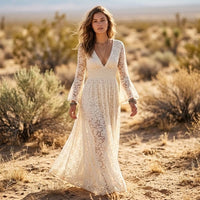 Woman wearing a white boho lace maxi dress with long bell sleeves, deep V-neckline, empire waist, and flowing A-line skirt.