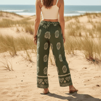 Woman showing the back of her Boho Olive Meadow wide leg palazzo pants in olive green with ivory boho print and relaxed rayon fabric.