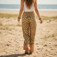 Back image of a woman wearing olive sage boho wide leg palazzo pants with a high waist drawstring waistband and vintage geometric print paired with a white tank top