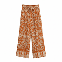 Rust paisley boho wide leg pants with functional side pockets, a high waist drawstring waistband, and a flowy palazzo silhouette.