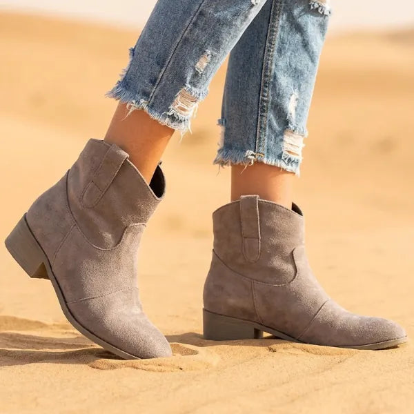 Women’s gray boho western ankle boots featuring a distressed-look finish, slouchy shafts, pointed toes, and low block heels.